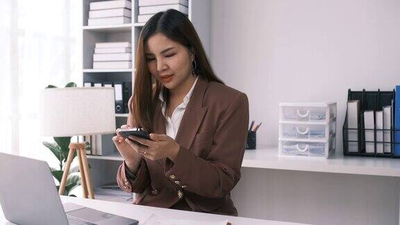 女性企业家女商人成功的亚洲女商人使用智能手机手机应用程序在线交流坐在办公室的桌子在室内