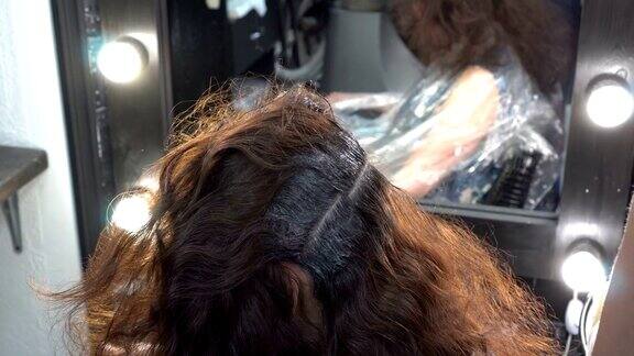 美发师:美发师在理发店染发过程中将颜料涂在一位东方女孩的头发上关闭了4k