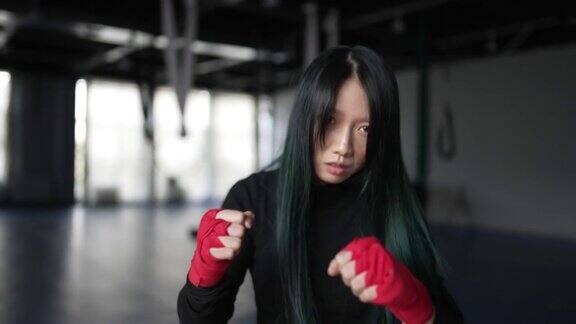 年轻的亚洲女拳击手在手指上缠着红色绷带练习拳击和格斗
