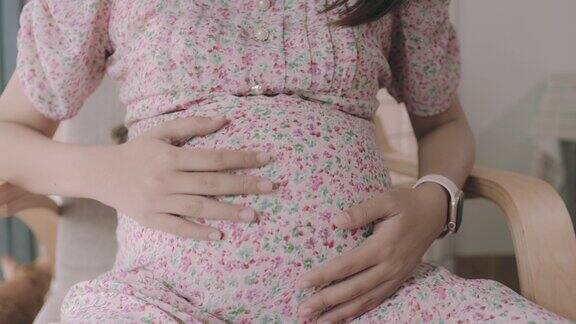 怀孕的亚洲妇女坐在屋子里放松开心地看着胎儿在子宫里的超声波照片