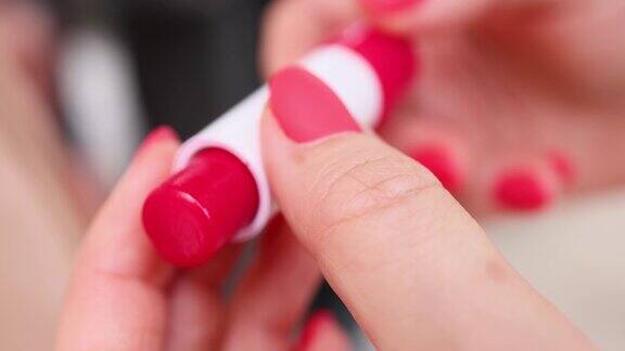 一只涂着红色指甲的女性张开又合上了一支红色唇膏天气会从包装中进出红色指甲油