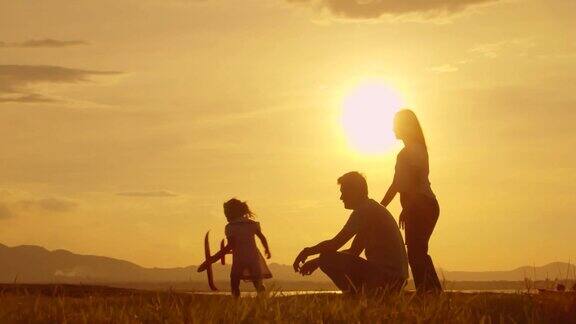 快乐的亚洲家庭爸爸妈妈和女儿在海滩上玩日落高清慢镜头