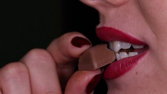 年轻女子的嘴咬着一块巧克力