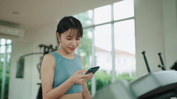 亚洲女子在健身房使用智能手机