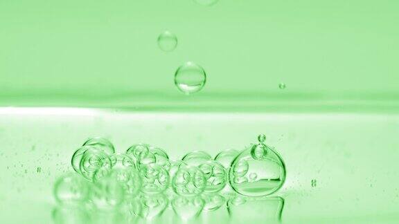 绿色的气泡下沉到绿色背景的液体表面
