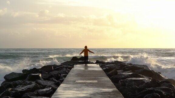 意大利莱万托一名男子站在码头上望着大海身穿黄色夹克夕阳西下