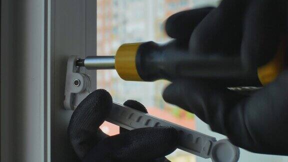 工人用螺丝刀将固定螺钉拧入窗框设置开窗调节器在塑料窗框上安装限位器窗框固定装置