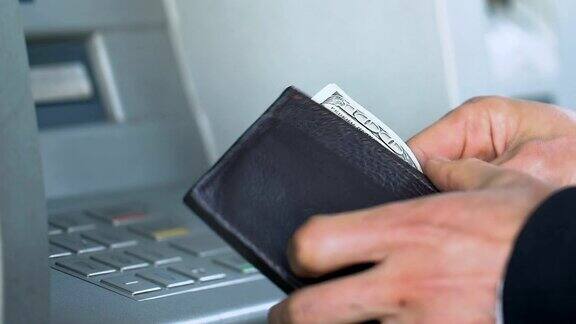 一名男子在自动取款机上输入个人密码然后收到钞票数钱