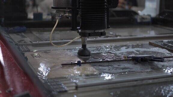在工业工厂里用水射流切割机切割高精度零件操作人员辛苦工作