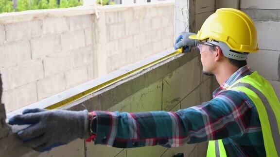 亚洲男建筑工人用工具施工卷尺检查房屋窗台的距离