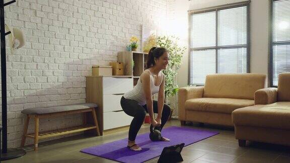 亚洲女性在家里的沙发上锻炼她是蹲