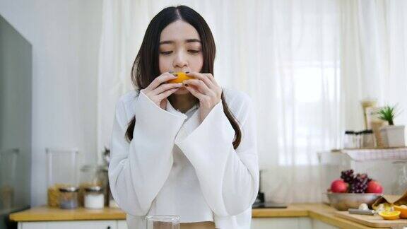 快乐的亚洲女人在厨房喝橙汁健康的饮食和健康