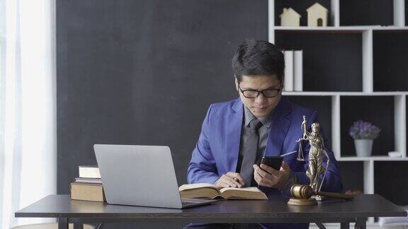 亚洲中年男性律师工作在笔记本电脑和法律合同文件在法庭锤子和女神鳞片的咨询和法律服务概念4k