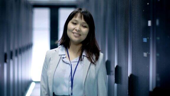 女性亚洲IT工程师微笑而站在数据中心满机架服务器的特写