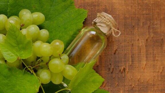 葡萄籽油在木板背景上木背景上的油瓶和一串绿葡萄用于面部和身体按摩和护理的基础化妆品油有机天然生物葡萄籽油
