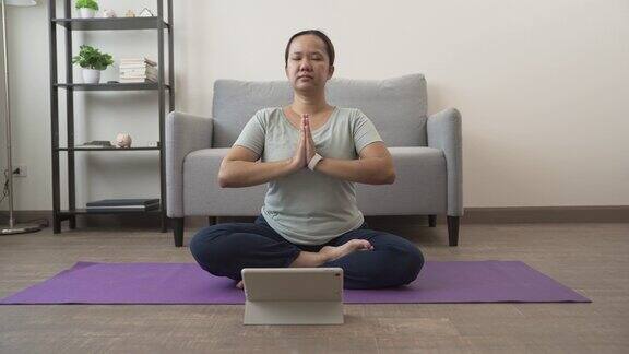 一个亚洲女人坐在家里的垫子上做瑜伽