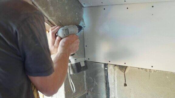 工人安装干墙使用螺丝刀和螺丝工作特写