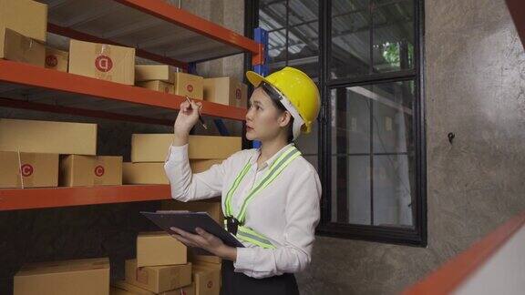 一名亚洲女性仓库工人在公司仓库现场检查库存交付