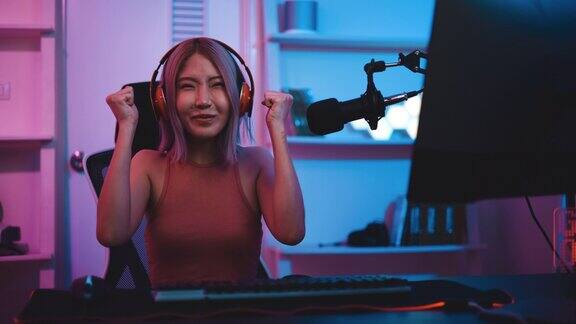 年轻的亚洲电子竞技女玩家在家里用霓虹灯在电脑上玩网络游戏