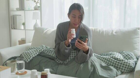 年轻的亚洲女孩患者通过手机视频通话咨询医生在家中远程医疗在线服务的医疗app上进行药物剂量说明居家隔离保持社交距离