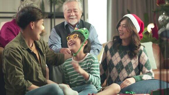 幸福亚洲家庭在家里一起度过欢乐的节日时刻多代家庭祖父母、父母和孩子在圣诞节期间在家里积极地笑着笑着交谈