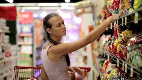 母亲带着小女儿在超市的糖果区挑选零食
