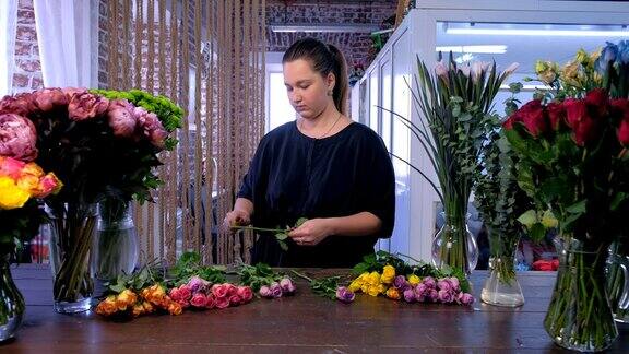 在花店的桌子上剪玫瑰刺的职业妇女花店