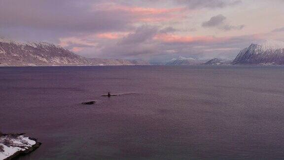 航拍4k视频在挪威戏剧性的冬季日落期间风景秀丽的turqouse海与地平线上的雪山