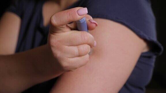 一个年轻女子注射胰岛素到她的手臂与胰岛素笔的特写