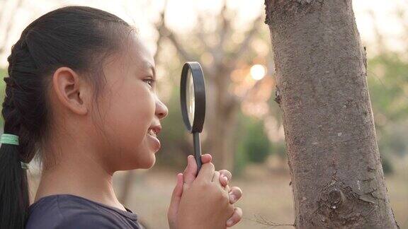 亚洲小女孩享受大自然用放大镜学习生物课