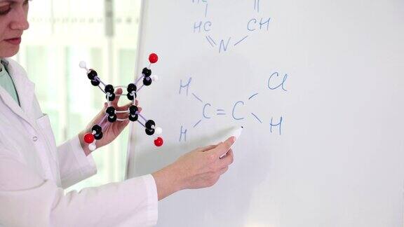 女科学家老师拿着分子模型在黑板上写化合物