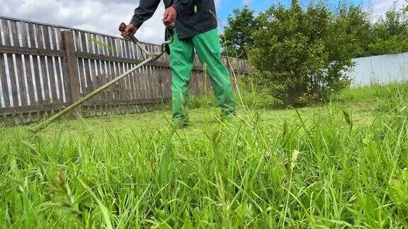 园丁修剪杂草一个人在院子里用剪绳机割草