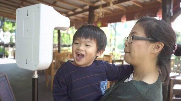 亚洲母亲抱着她的儿子测量体温的数字热扫描