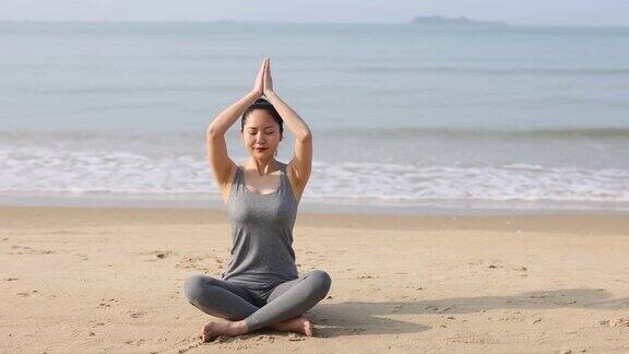 年轻的亚洲女人在海滩上做瑜伽