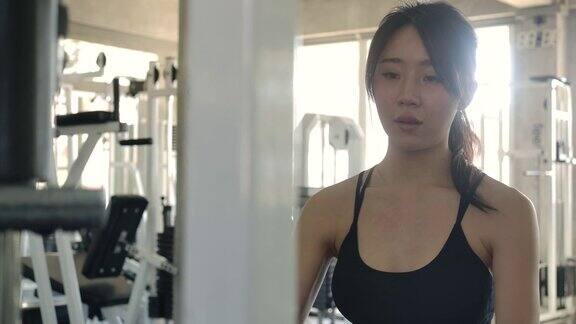 迷人的女人做运动在交叉机器在健身房年轻的运动亚洲女子训练与举重训练机器在健身中心缓慢的运动运动和运动概念