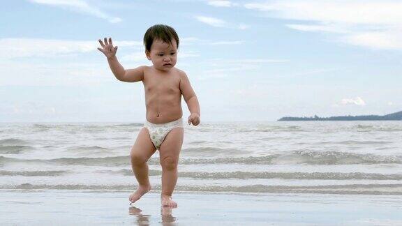 快乐的亚洲小男孩儿子学习走在热带海滩上有乐趣沿着边缘的日落海浪在沙滩上