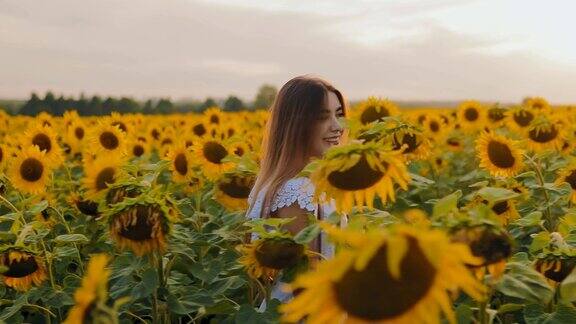 快乐美丽的女孩走在鲜花草地上向日葵侧视图