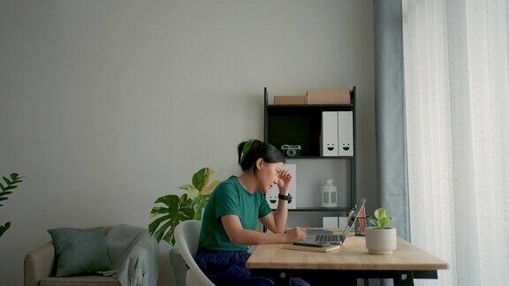 亚洲女性使用笔记本电脑担心工作坐在家里办公室