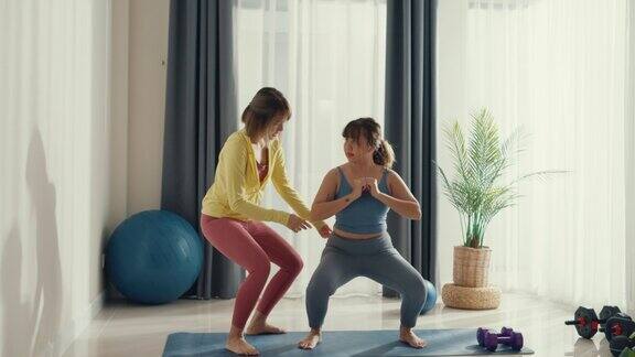 年轻的亚洲运动健身女性在女私人教练的帮助下在家里的客厅锻炼