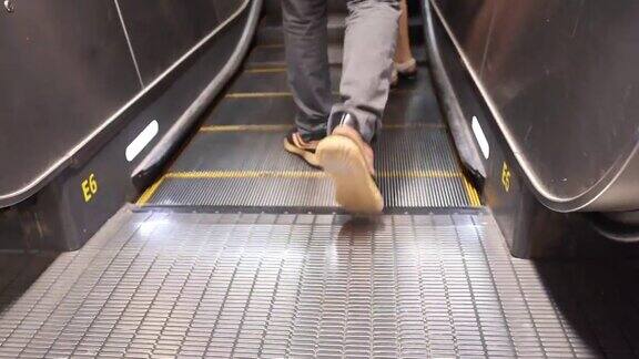 在机场公共区域将搭乘自动扶梯的人群的腿部进行特写