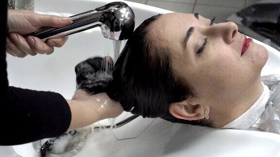 一个东方女孩在理发店剪完头发染发后洗了头的特写头发护理关闭了4k25fps