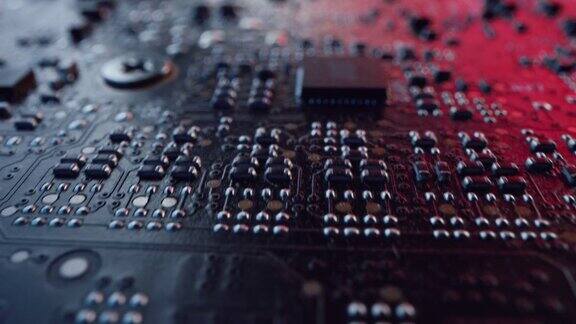 微距相机在印刷电路板上缓慢移动显示计算机主板组件:晶体管电阻电容半导体电子设备内部红色霓虹灯的颜色