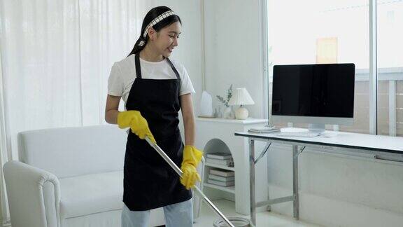 一个打扫房子的女人的特写镜头她一边打扫桌子一边用喷雾器和蓝色布擦灰尘房屋清洁概念