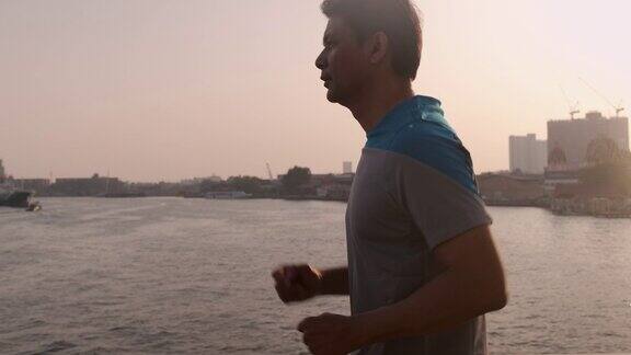 侧面拍摄的亚洲资深男子快速走过大桥在日落