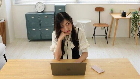 一位忧心忡忡的日本妇女在小办公室里远程工作