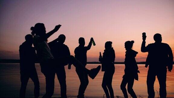 日落时分一群跳舞的年轻人在海滩上举行聚会