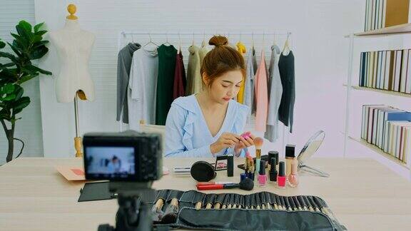 美丽博主视频博客展示化妆品坐在镜头前录制视频快乐美丽的年轻亚洲女性网红播送如何在社交网络