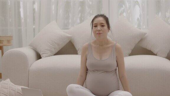 怀孕的母亲为了她未出生的孩子的健康练习瑜伽呆在家里