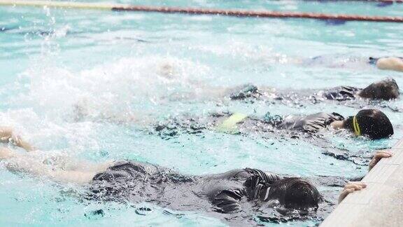 亚洲中国游泳运动员在游泳教练的指导下在泳池边练习腿溅水