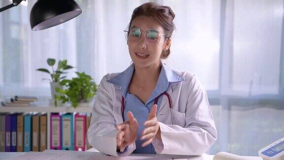 年轻漂亮的亚洲女医生在医务室看着镜头与病人进行着在线会诊年轻女医生用听诊器进行视频通话